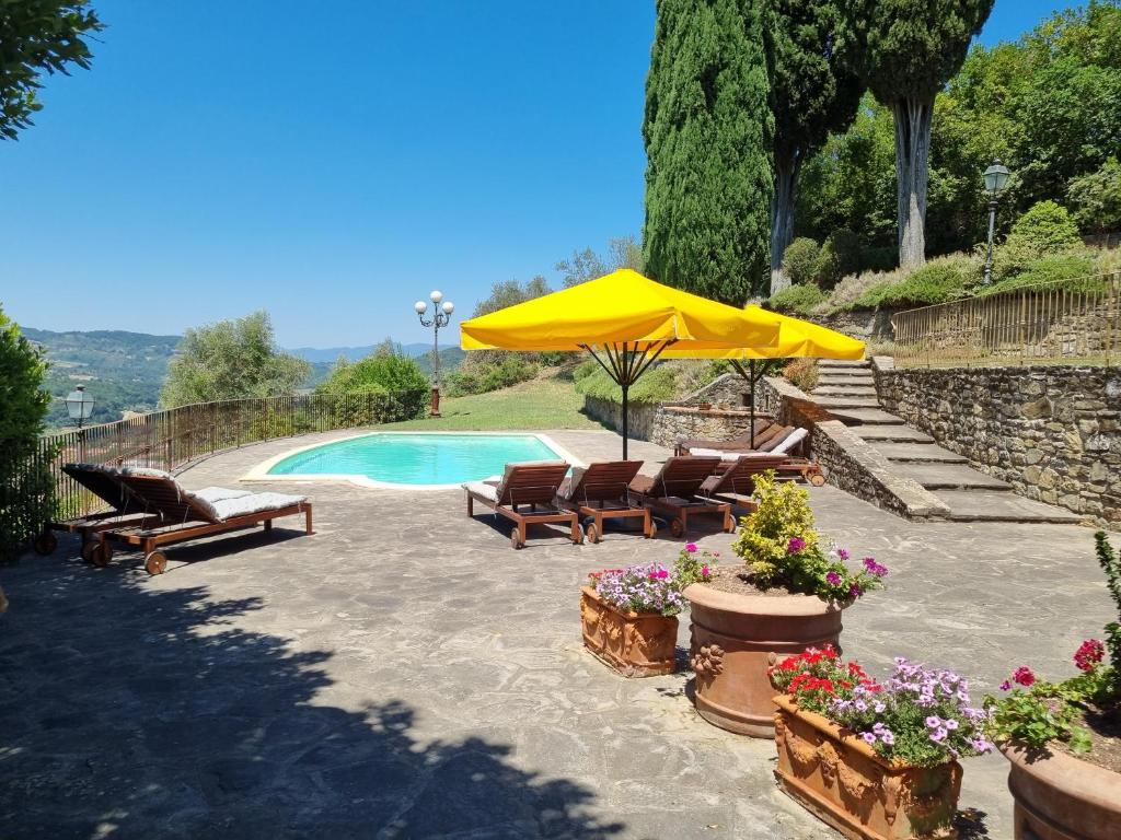 un patio con sillas, una sombrilla y una piscina en Podere Vecci, en Dicomano