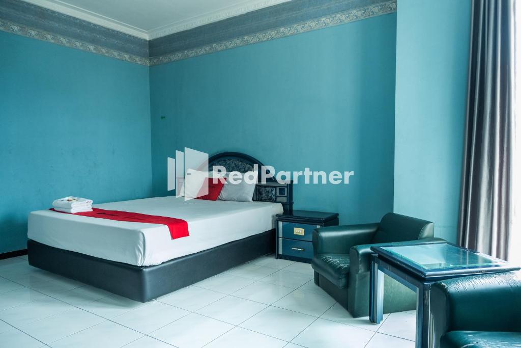 a bedroom with a bed and a chair and a table at Akur Hotel Malioboro Mitra RedDoorz in Yogyakarta
