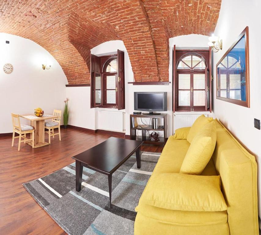 a living room with a yellow couch and a table at Dom Unirii Apartment in Timişoara