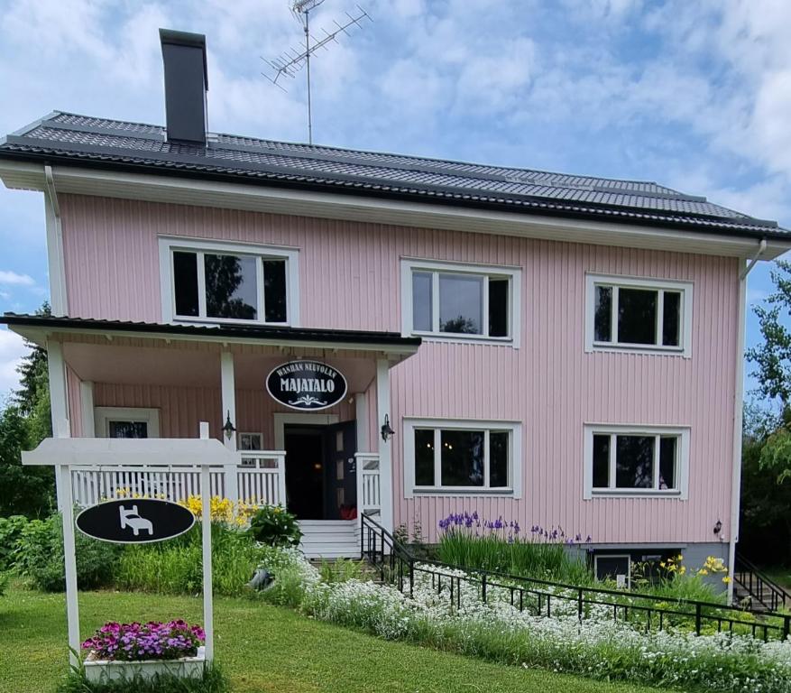 uma casa cor-de-rosa com um cartaz à frente. em Wanha Neuvola Guesthouse & Apartment em Pieksamaki