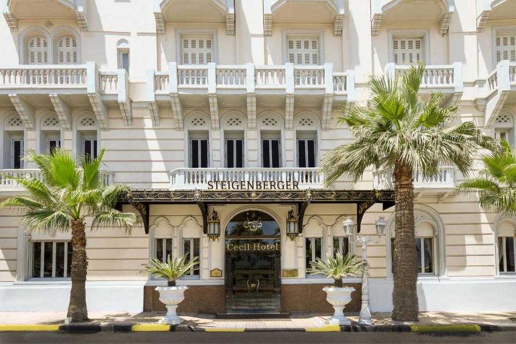 un bâtiment avec des palmiers en face de celui-ci dans l'établissement Steigenberger Cecil Hotel Alexandria, à Alexandrie