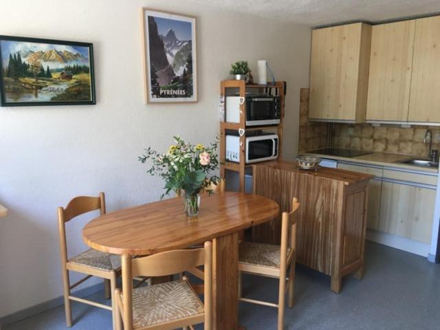 una cocina con una mesa de madera con un jarrón de flores. en Studio St Lary proche du centre, au calme avec vue montagne, en Saint-Lary-Soulan