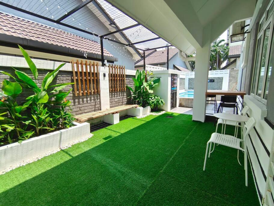 eine Terrasse mit grünem Gras sowie einem Tisch und Stühlen in der Unterkunft RUMAH AINA Homestay Bukit Changgang Private Pool in Kampong Melot