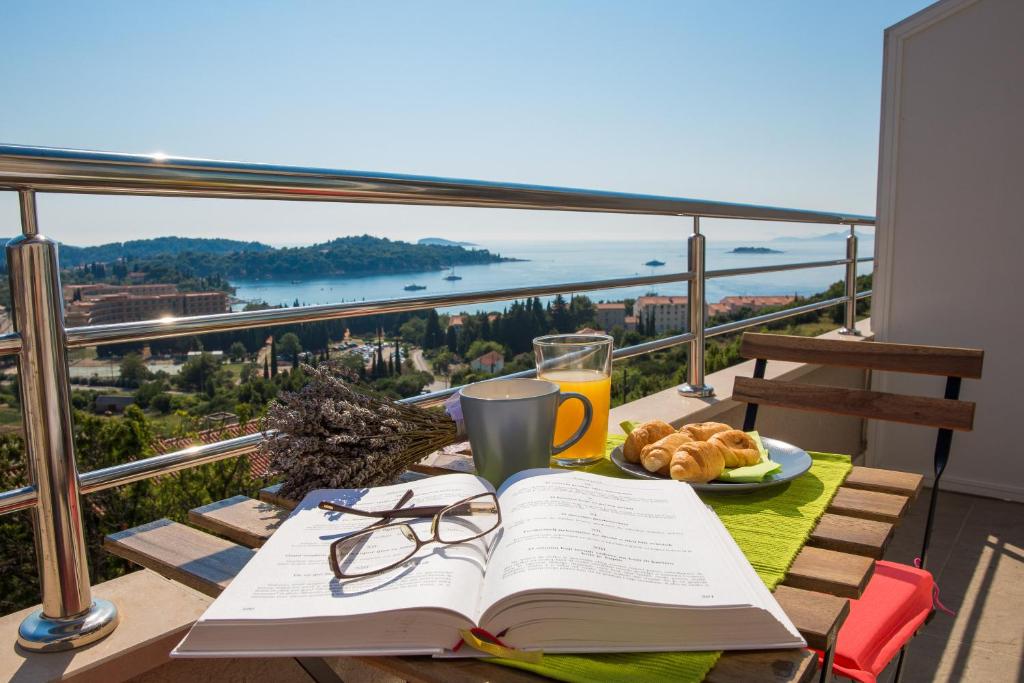 einen Tisch mit einem offenen Buch und einem Teller mit Essen in der Unterkunft Mediterranean Sunset Apartments in Cavtat