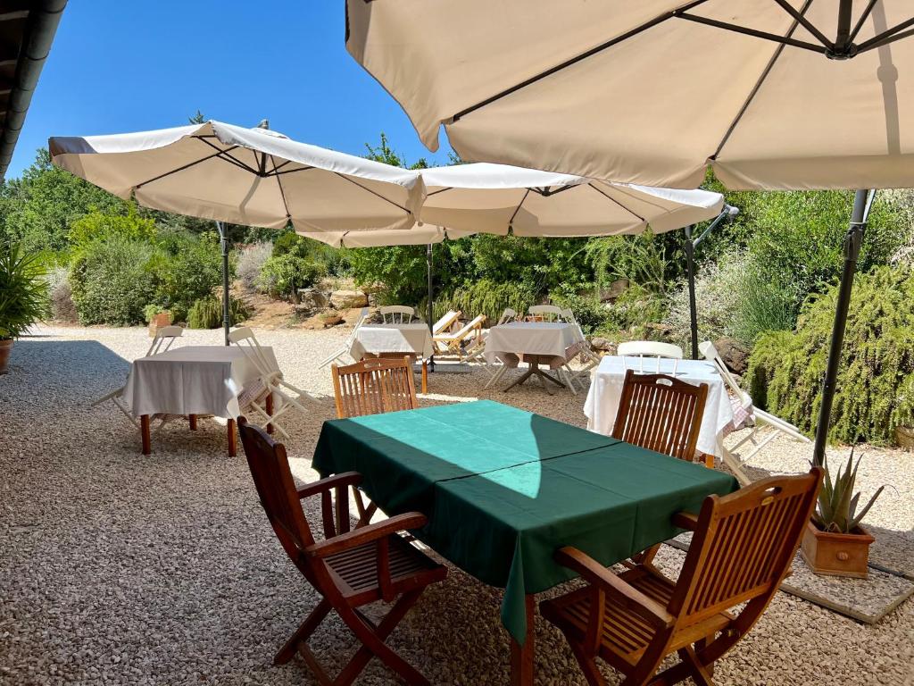 a green table and chairs with umbrellas at Casale Terre Rosse in Saturnia
