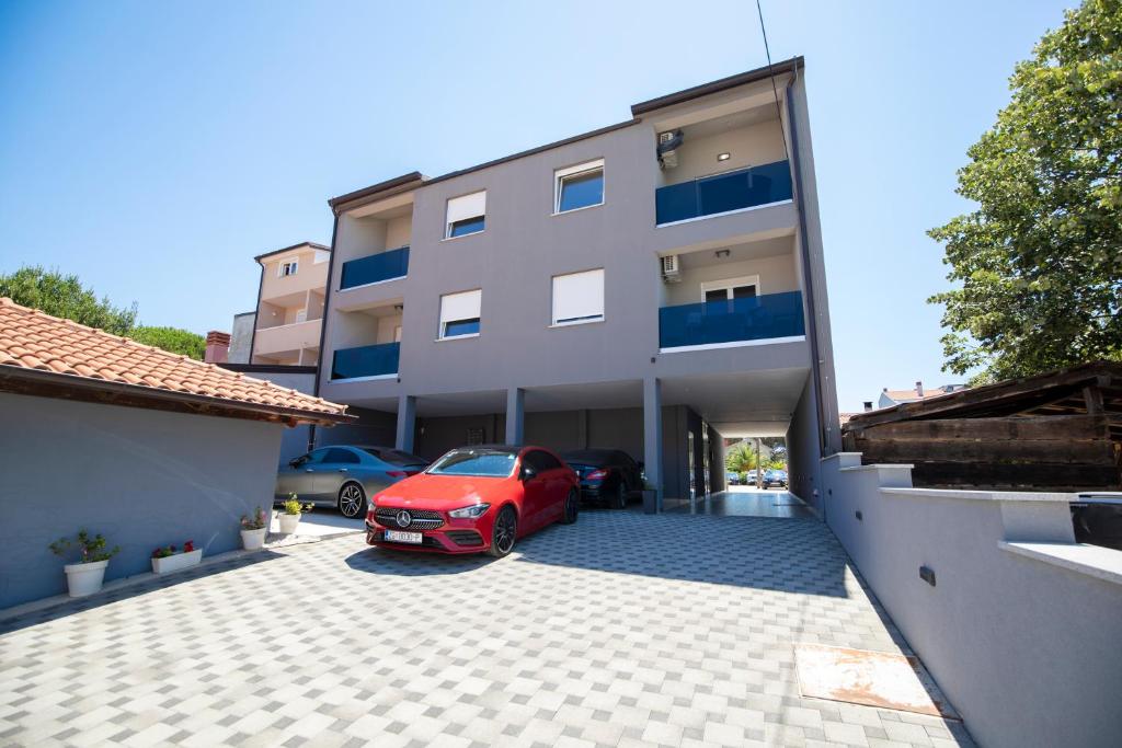 a red car parked in a parking lot in front of a building at Residence Panorama in Medulin