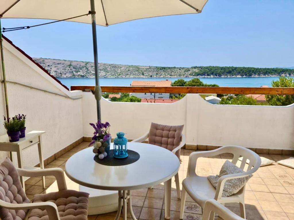 a patio with a table and chairs and an umbrella at Sunny view Apartman in Barbat na Rabu