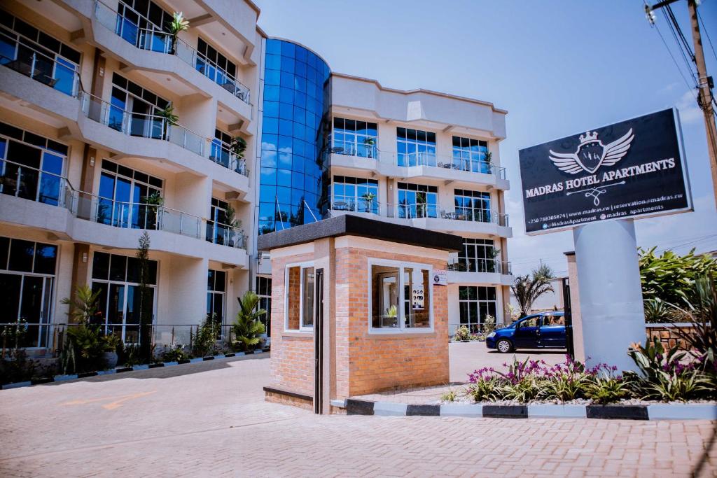 un edificio de ladrillo con una señal frente a un edificio en Madras Hotel and Apartments, en Kigali