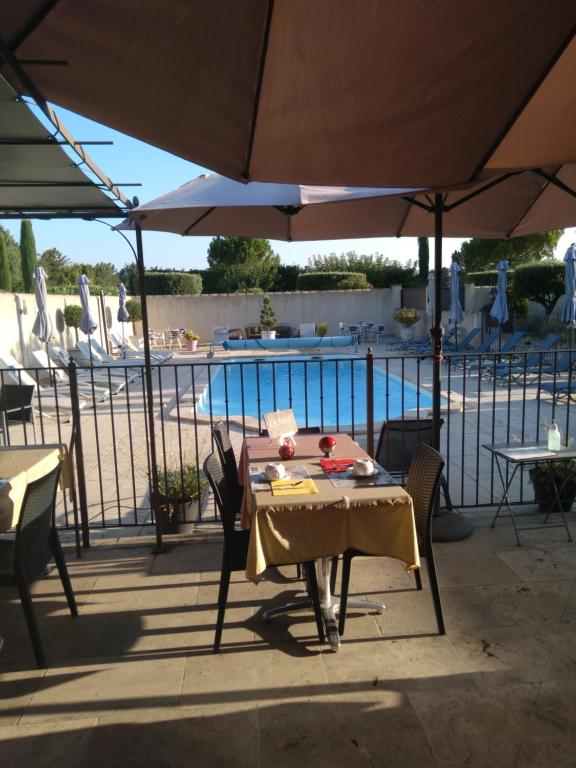 - une table et des chaises sous un parasol à côté de la piscine dans l'établissement Mas Dansavan Chambres d'hôtes, à Oppède