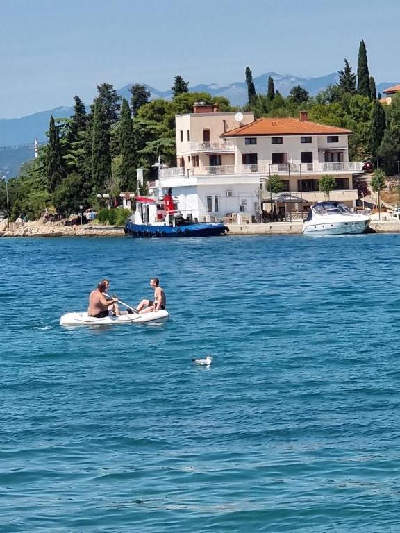 zwei Männer in einem Boot auf einem Wasserkörper in der Unterkunft Villa Riva in Omišalj