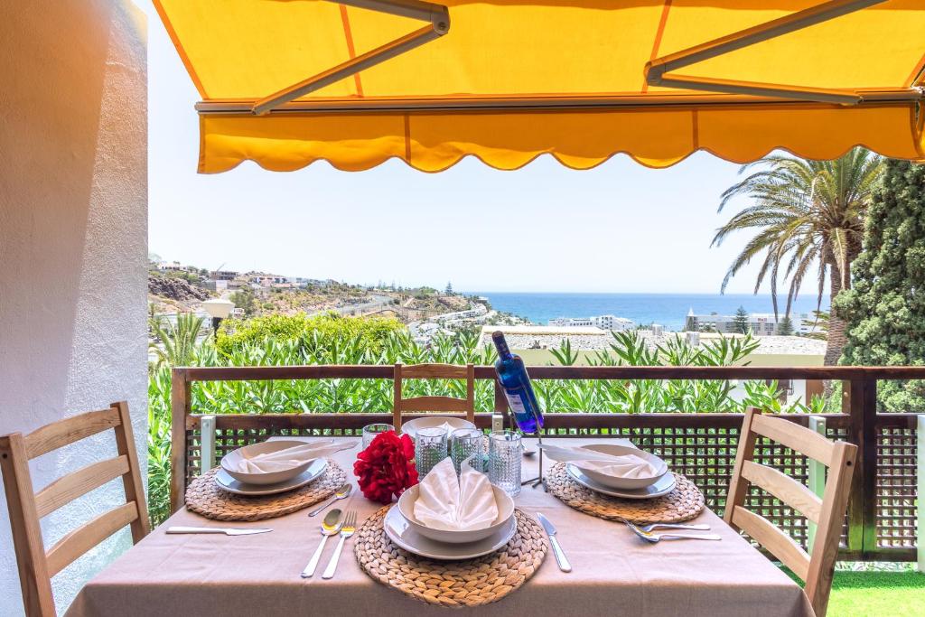 einen Tisch mit Tellern und Küchenutensilien auf einem Balkon mit Meerblick in der Unterkunft Increible Terraza con vistas al mar en San Agustín (3 hab) in San Agustín