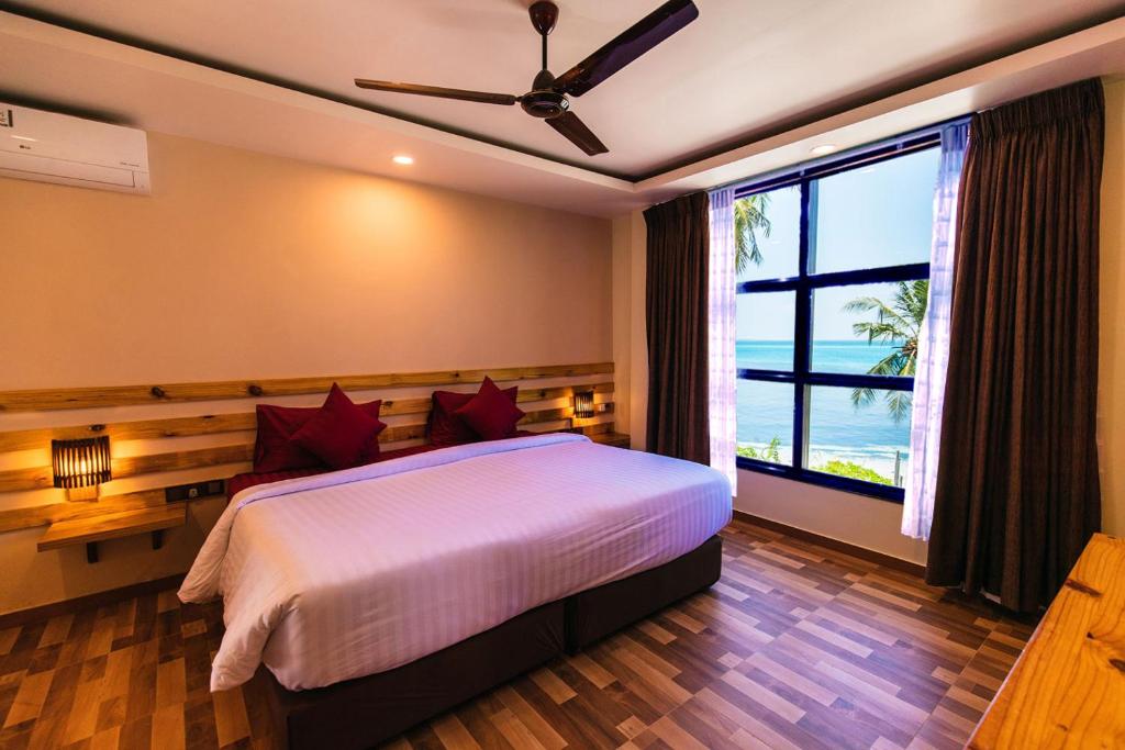a bedroom with a bed with a view of the ocean at Endheri Sunset Dhangethi in Dhangethi