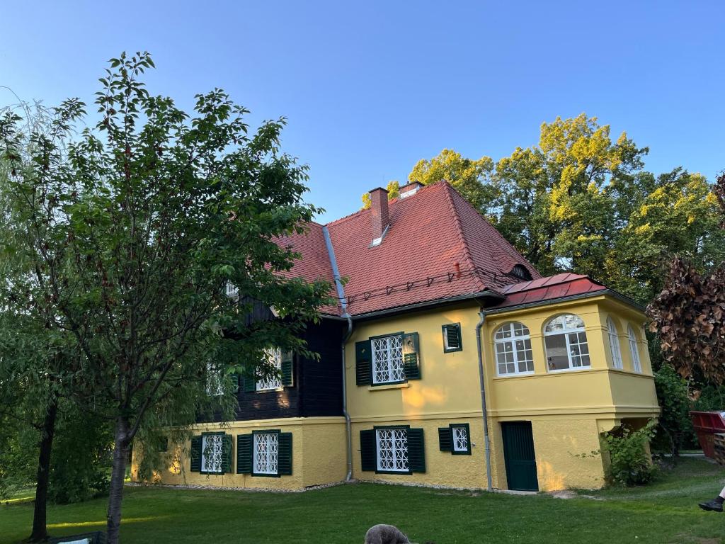 ein gelbes Haus mit rotem Dach in der Unterkunft Landvilla im Park 