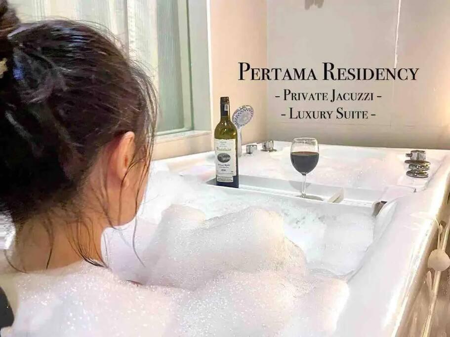 Eine Frau, die in einer Badewanne mit einer Flasche Wein sitzt. in der Unterkunft Private Jacuzzi Luxury Suite at KL City 178 in Kuala Lumpur