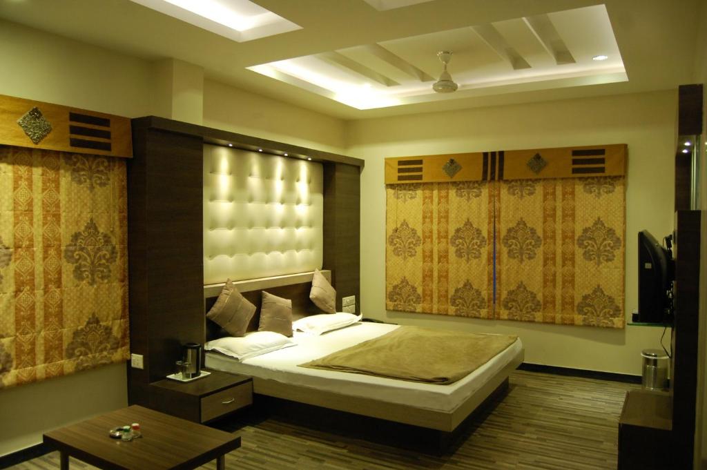 a bedroom with a large bed and a table at Hotel Purva in Indore