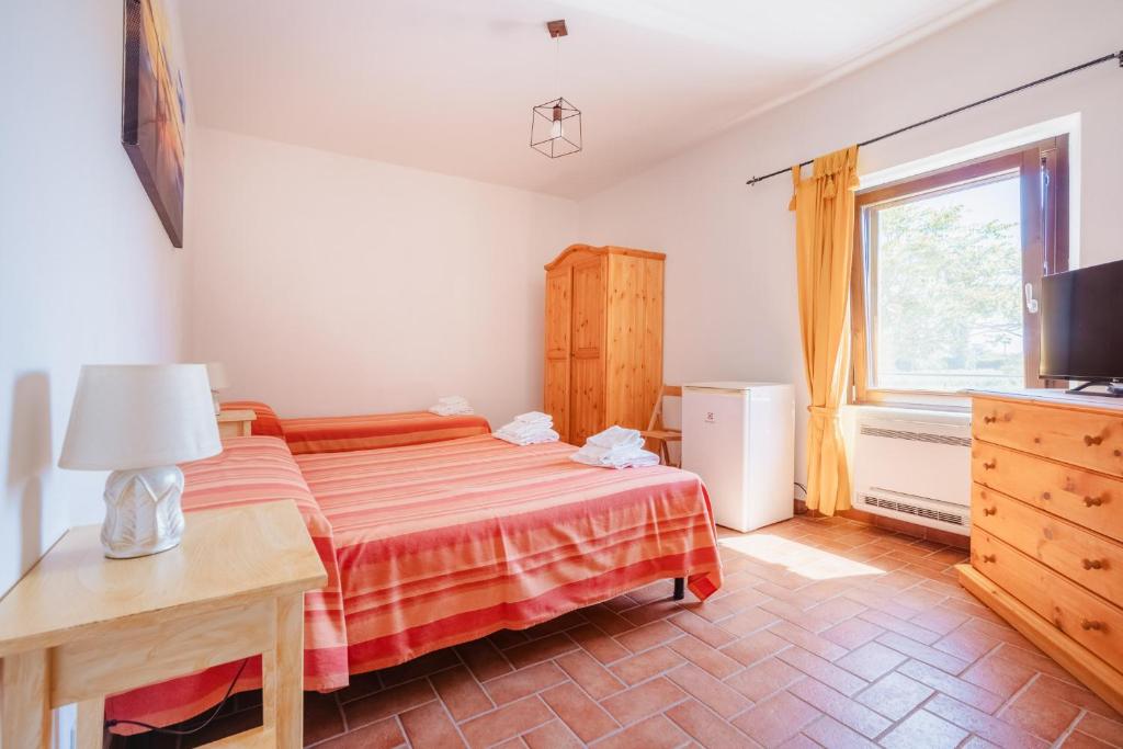 a bedroom with a bed and a television and a window at Agriturismo Ristorante Monte Argentario in Monte Argentario