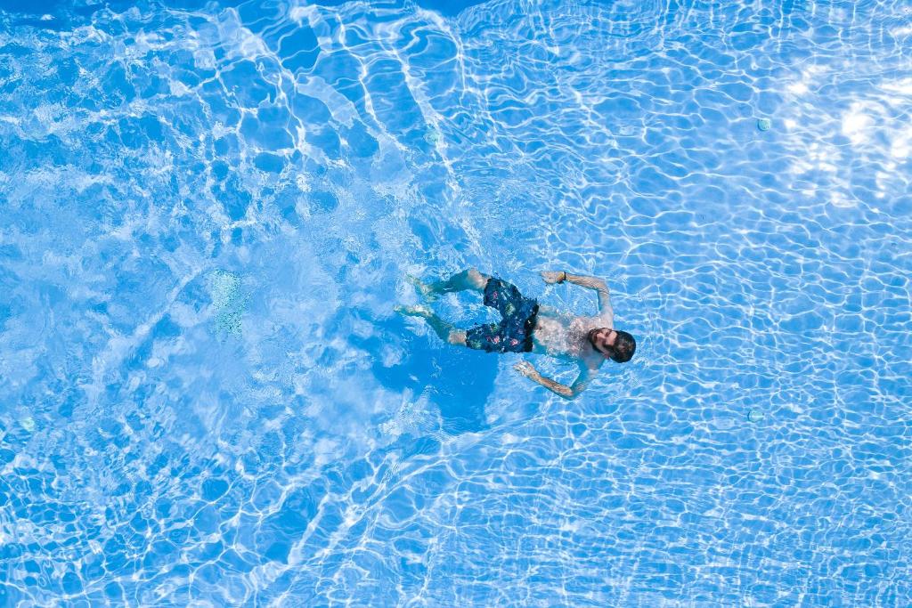 um homem está nadando em uma piscina de água em Mandilaria Studios em Perissa