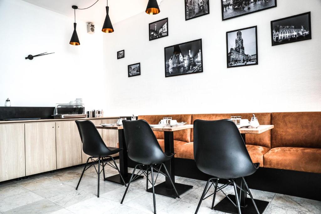 a restaurant with black chairs and a bar at Hotel Montovani in Bruges