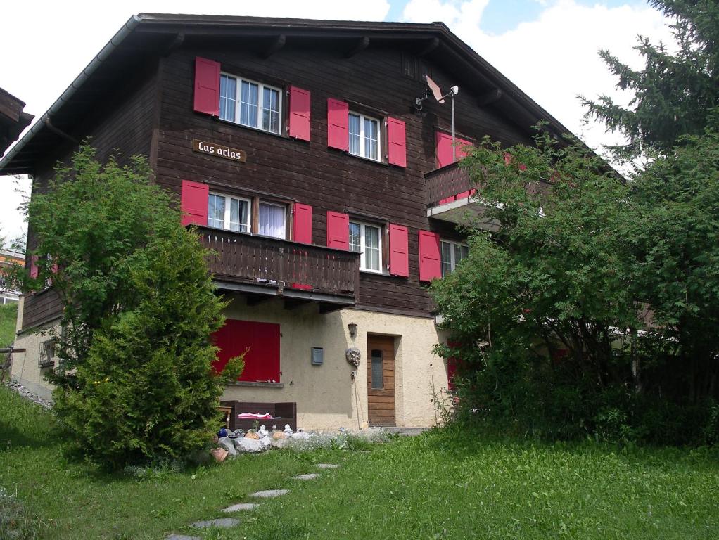 ein Haus mit roten Rollläden an der Seite in der Unterkunft Las aclas in Valbella