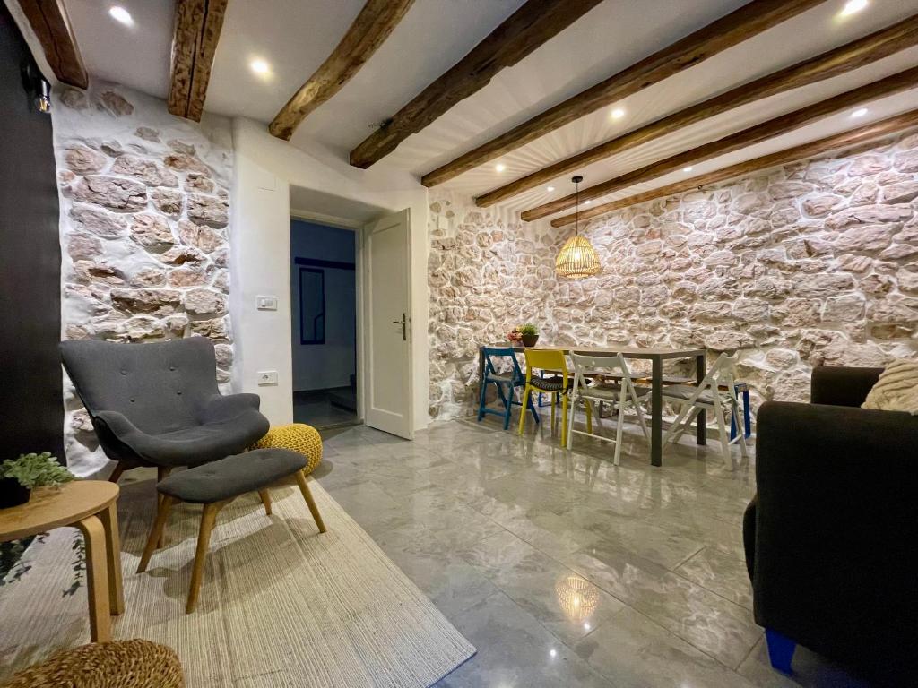 ein Wohnzimmer mit einer Steinmauer, Stühlen und einem Tisch in der Unterkunft Bell Tower House in Novi Vinodolski