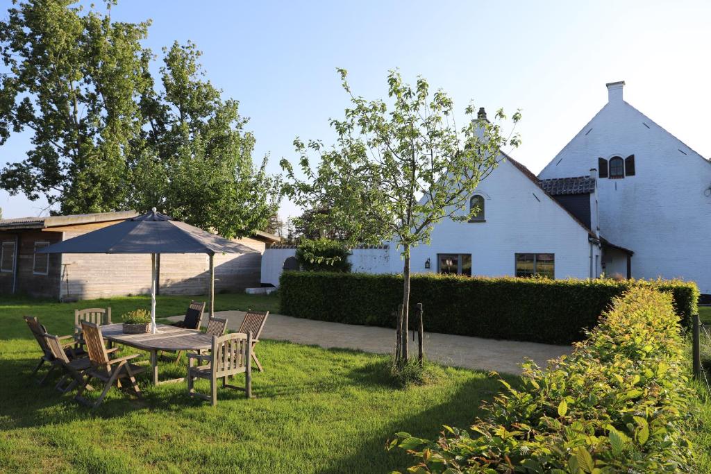 a table with an umbrella in the yard of a house at Zee-van-Tijd in Oudenburg