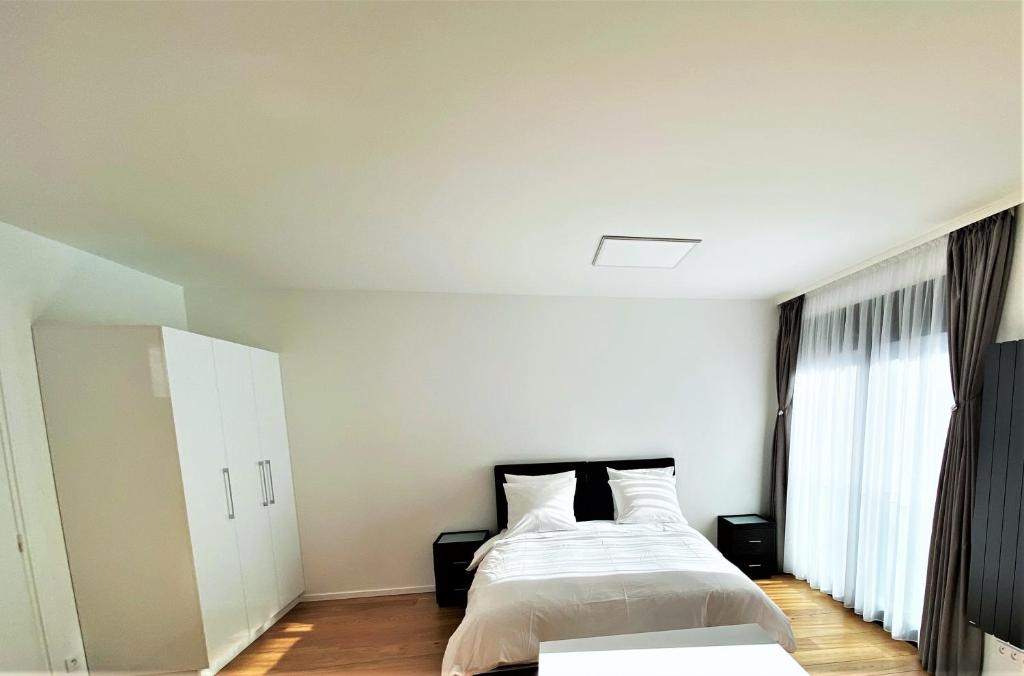 a white bedroom with a bed and a window at Studio de standing in Malakoff