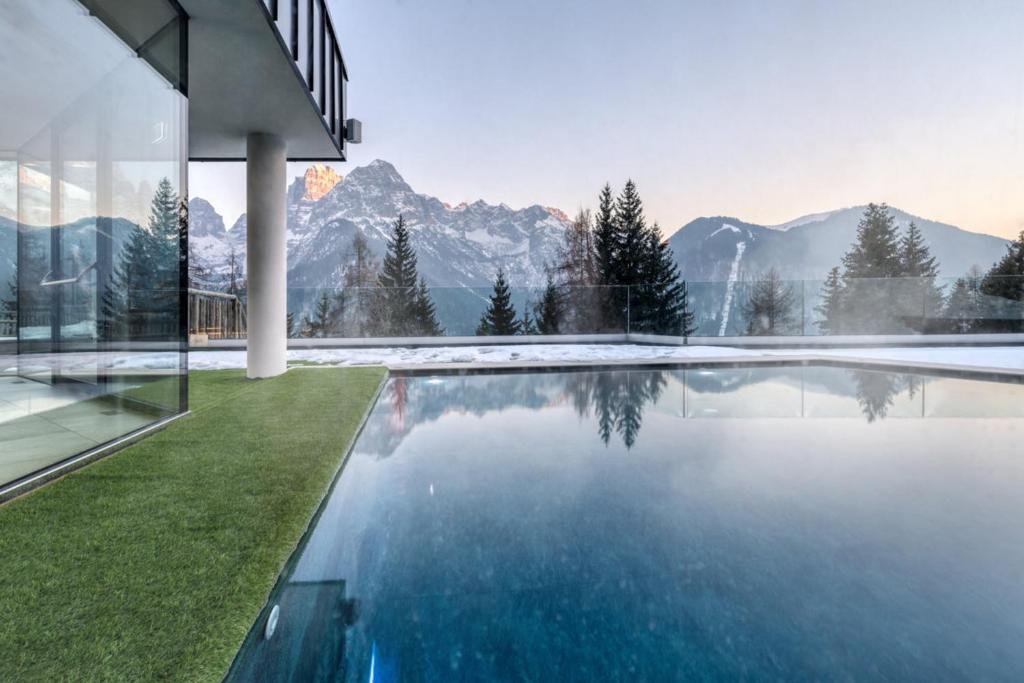 a house with a swimming pool with mountains in the background at Panorama Hotel Fontanella in Madonna di Campiglio