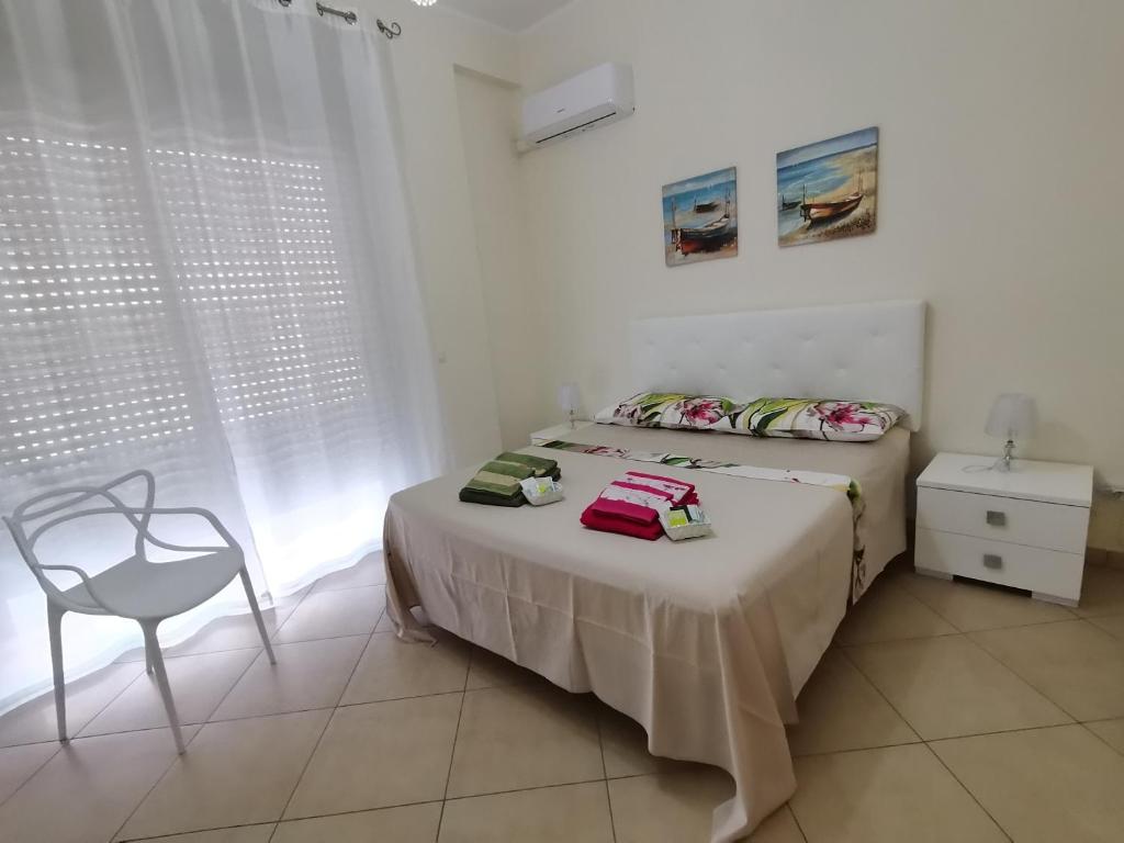 a white bedroom with a bed and a chair at Appartamento Relax in centro in Capo dʼOrlando