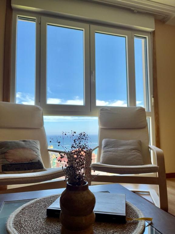a living room with two chairs and a table at Apartamento Arao Malpica con vistas al mar in Malpica