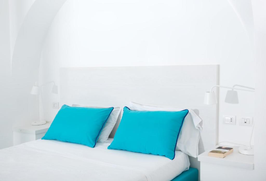 a white bed with two blue pillows on it at Hotel Le Terrazze in Conca dei Marini