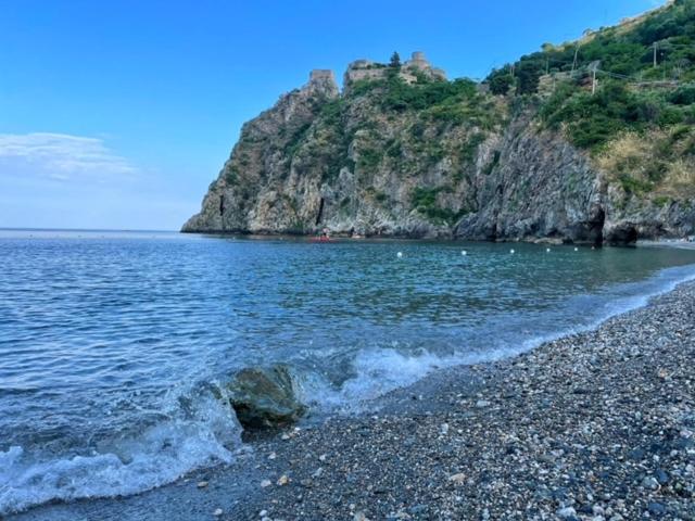 una playa rocosa con un castillo en la cima de una montaña en Incantevole appartamento Taormina, en SantʼAlessio Siculo