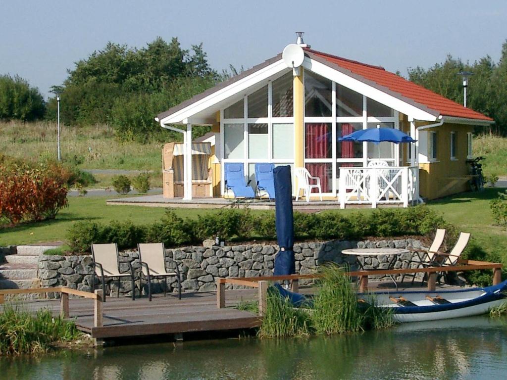 a house with a table and chairs and a boat in the water at 6 person holiday home in Otterndorf in Otterndorf
