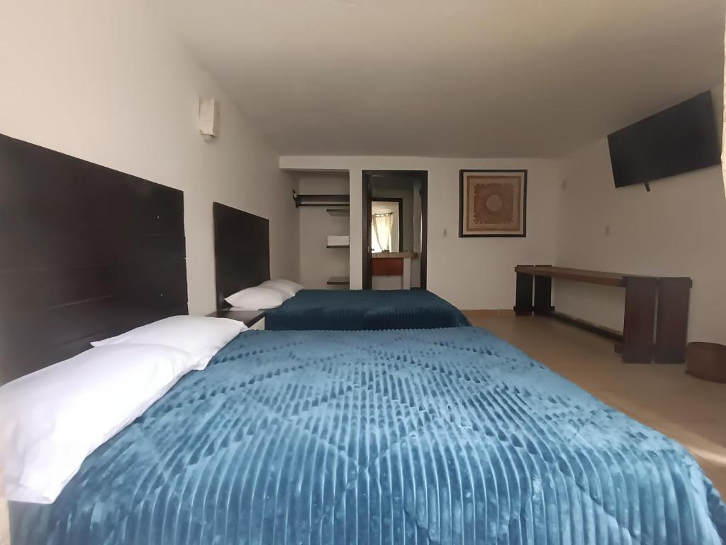 a bedroom with a large bed with a blue comforter at El Arrayan in Valle de Bravo