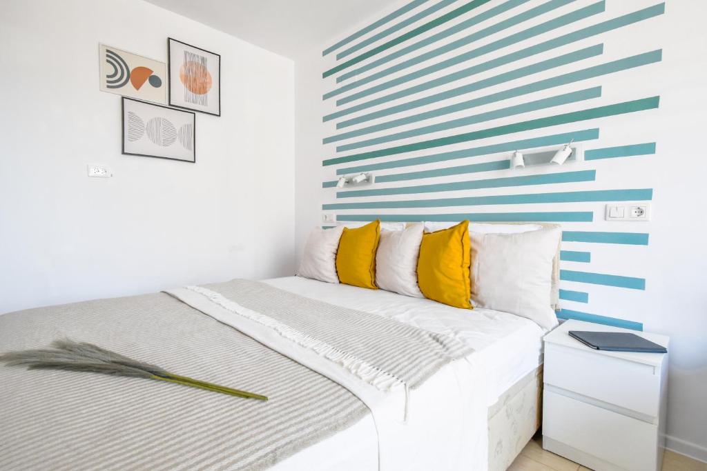 een witte slaapkamer met een blauwe en witte streepmuur bij Modern Studios - Meters away from the beach in Pomorie