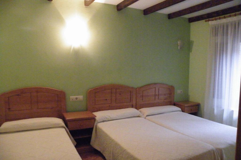 2 camas en una habitación con paredes verdes en Allotjaments Colomer-Cullell, en Bas
