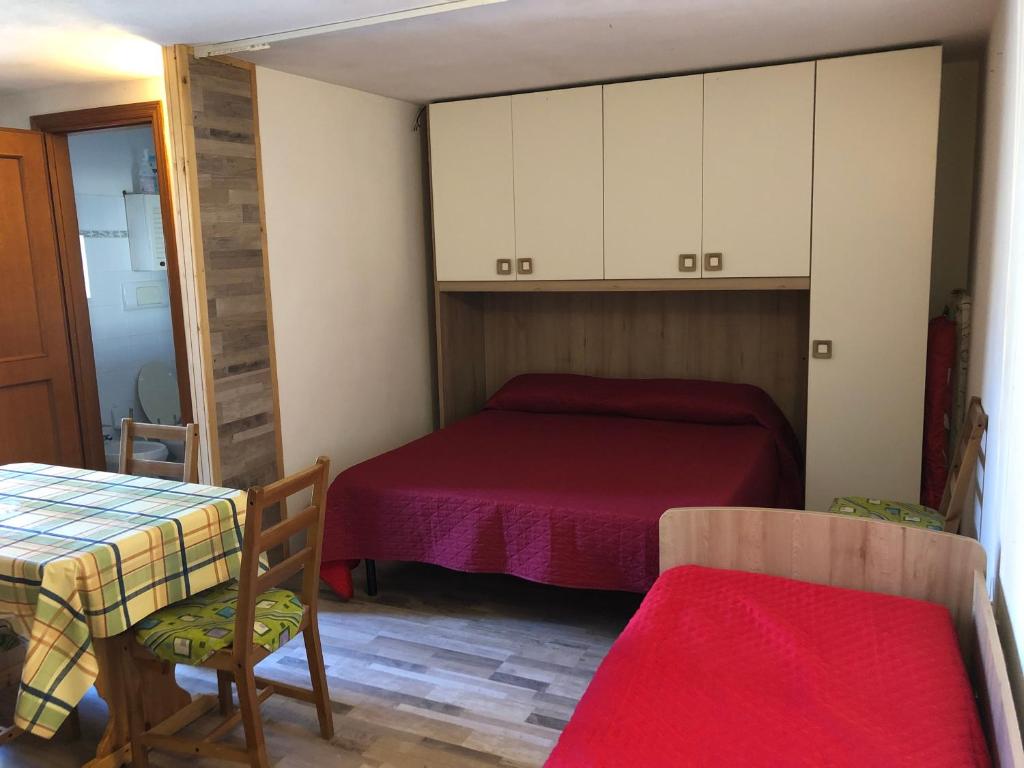 1 dormitorio con 1 cama, mesa y sillas en Monolocale Paduledda en Cascabraga