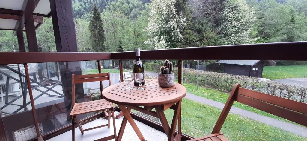 una mesa con 2 sillas y una botella de vino en el balcón en Un havre de paix aux pieds des chemins de montagne, en Les Contamines-Montjoie