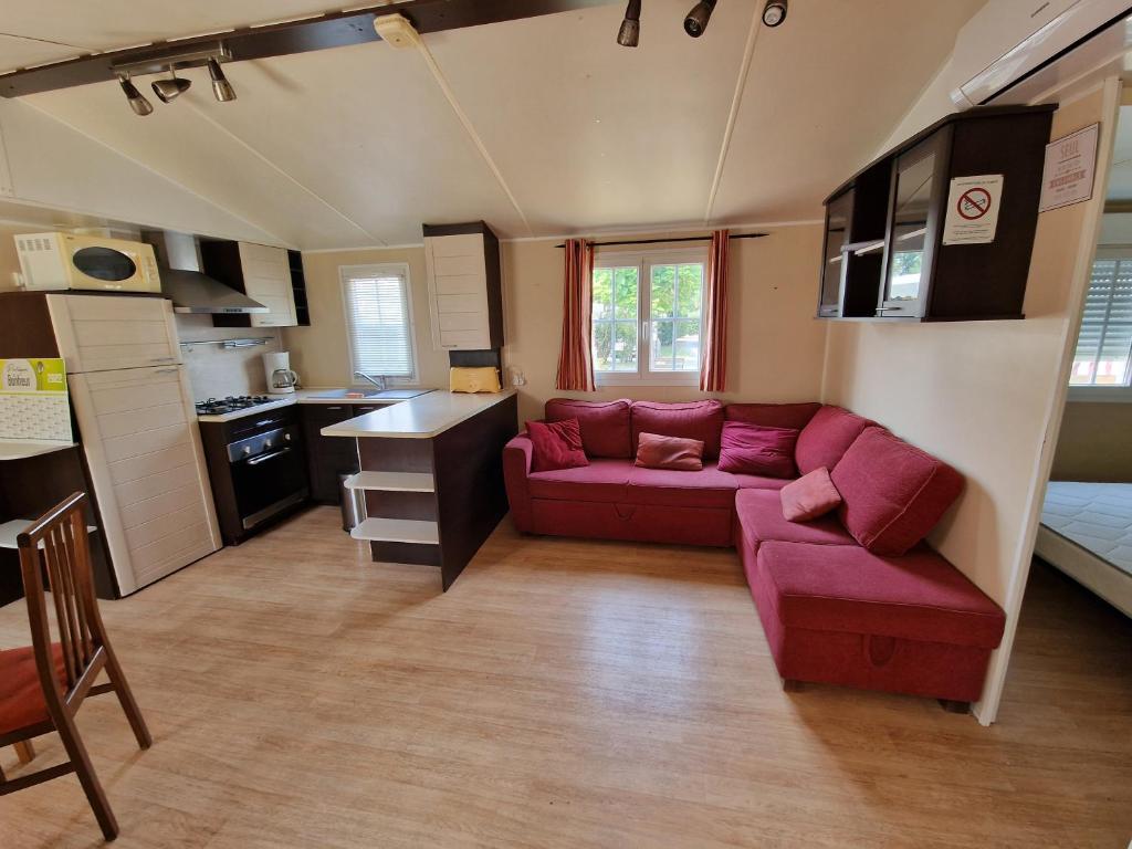 ein Wohnzimmer mit einem roten Sofa und einer Küche in der Unterkunft Grand Mobile home dans camping in Mimizan