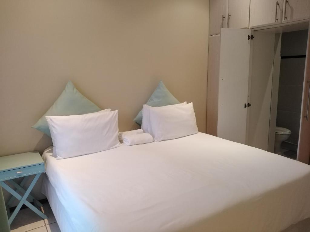 uma grande cama branca com duas almofadas em Posh 2 em Durban