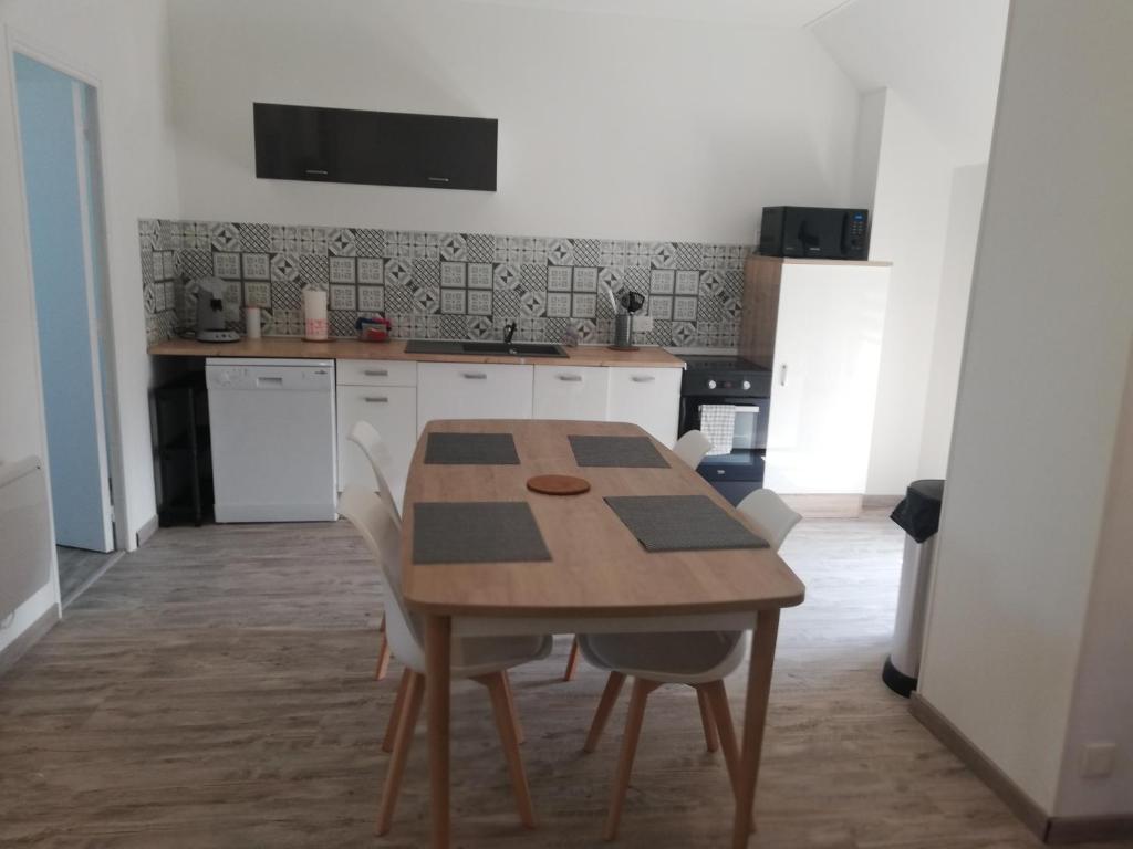 a kitchen with a wooden table and white cabinets at appartement neuf in Villers-Outréaux