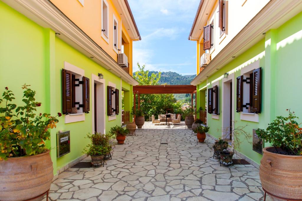 a courtyard with green and yellow buildings with potted plants at EXELLENT GUEST VILLA PRESTIGE in Asprogerakata