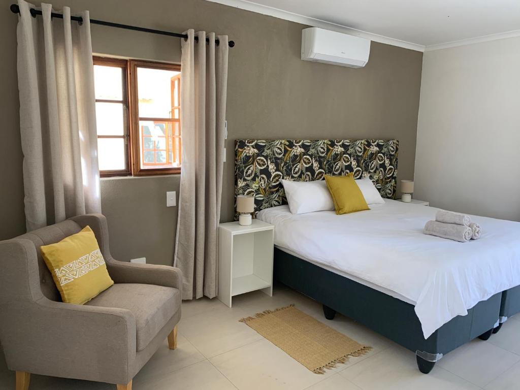 a bedroom with a bed and a chair at Otjibamba Lodge in Otjiwarongo