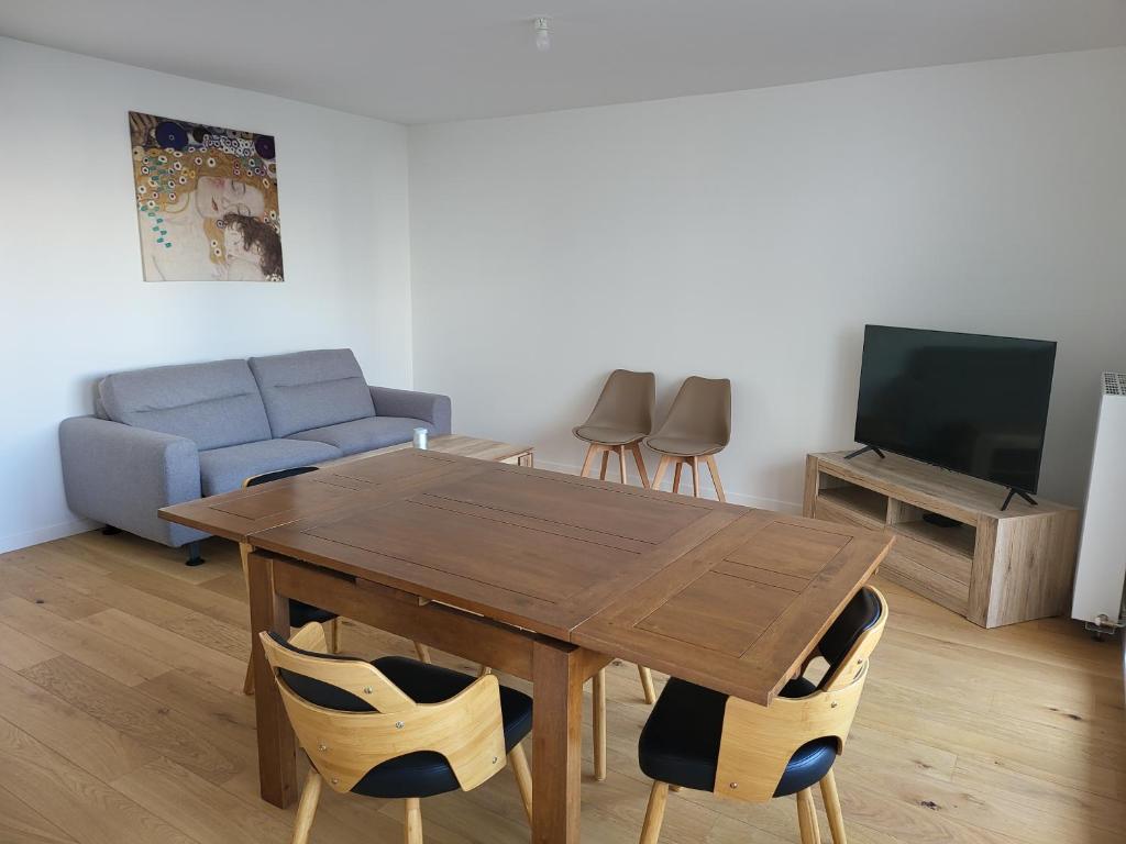uma sala de estar com uma mesa de madeira e cadeiras em Superbe Appartement à 3min à pieds de la gare em Chessy