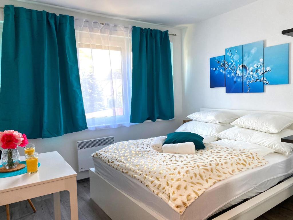 a bedroom with a large bed with blue curtains at Heléna Apartman Juventus in Balatonföldvár