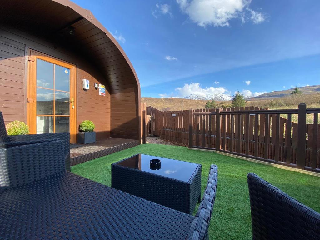a patio with two chairs and a table on the grass at Highland Stays - Ben View Studio Pod & Jacuzzi Bath in Fort William