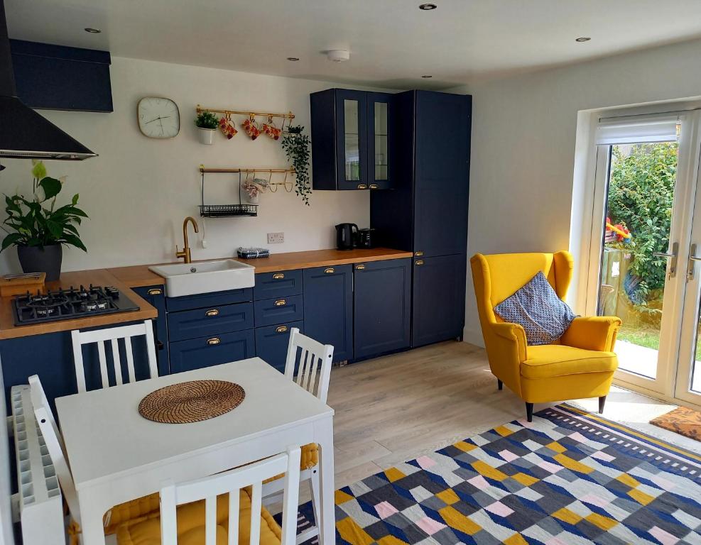 a kitchen with blue cabinets and a table and a yellow chair at Sunny Side - Self Catering Accommodation Gorey in Gorey