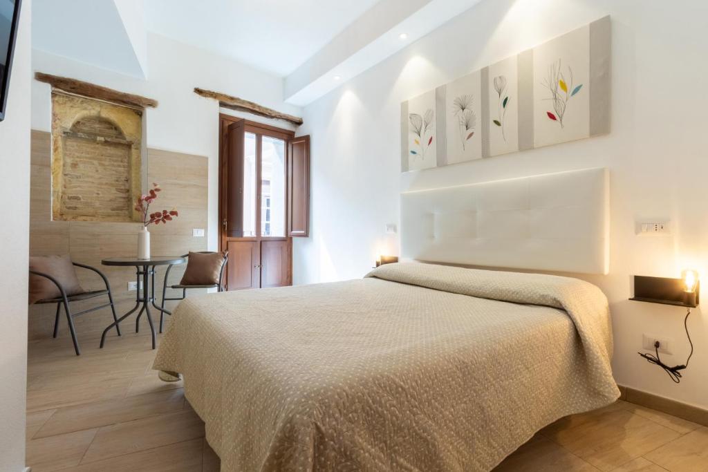 a bedroom with a large bed and a table at Rooms Best Vacation Ever in Cagliari