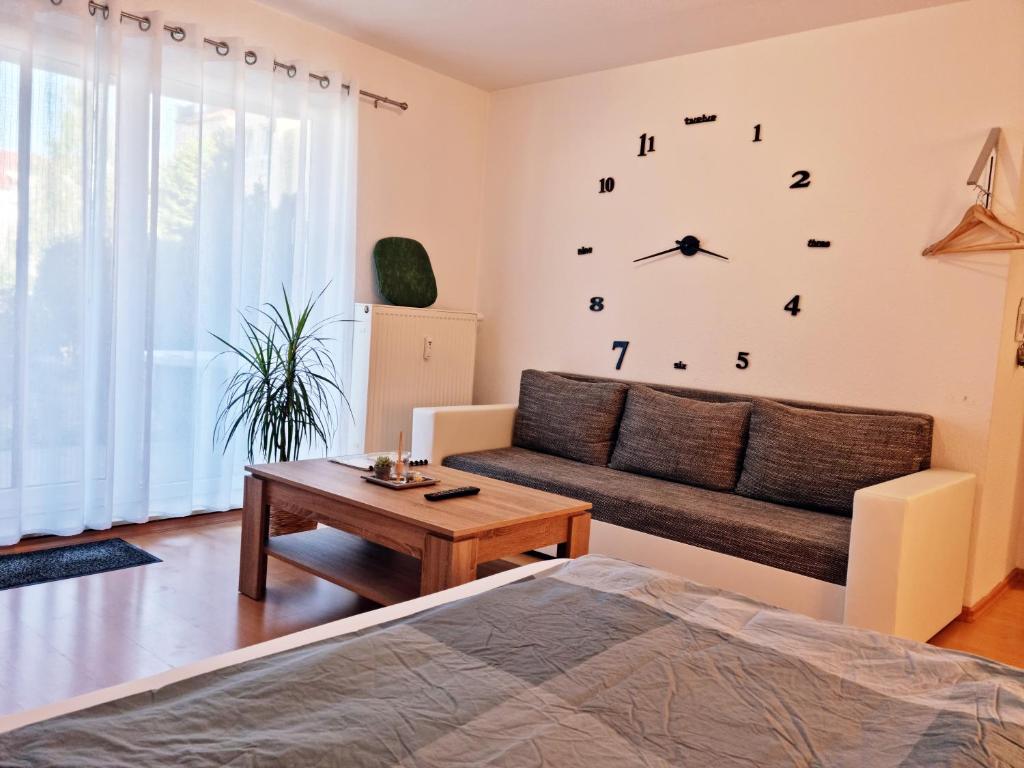 a living room with a couch and a clock on the wall at BRISE Business Apartment nahe Leipziger Messe - Porsche - BMW - DHL - WLAN - Parkplatz - business travelers only in Leipzig