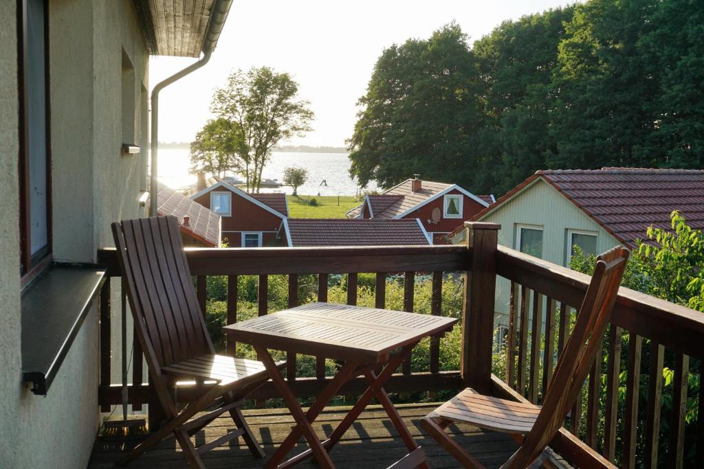einen Holztisch und zwei Stühle auf dem Balkon in der Unterkunft Ferienwohnung mit Seeblick und Strand in Zislow