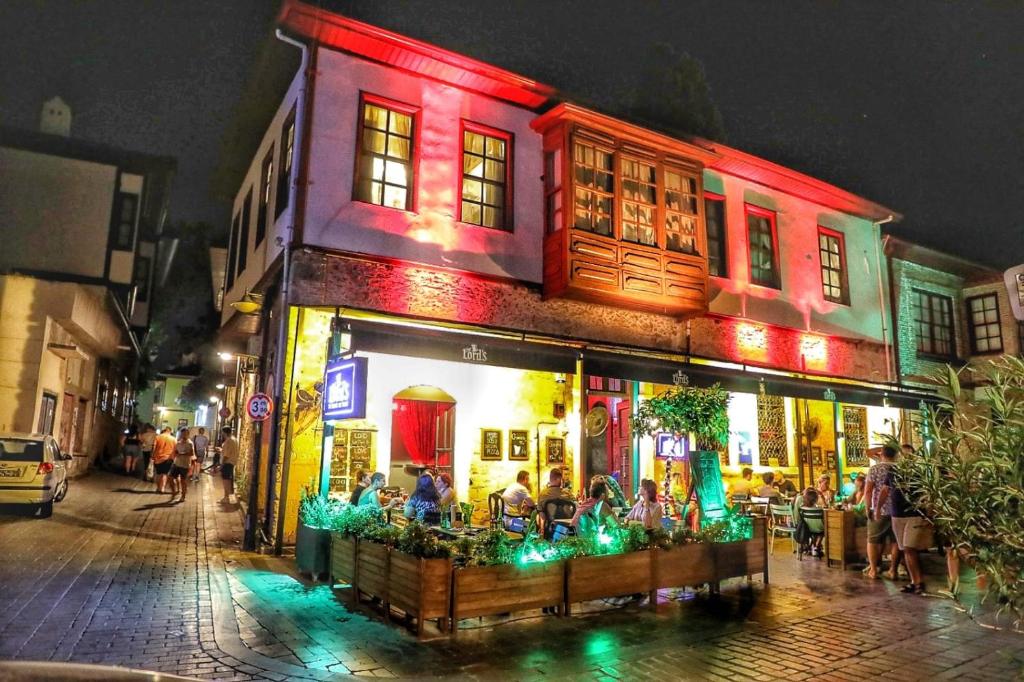 a group of people sitting outside of a restaurant at night at LORDS HOSTEL & PUB in Antalya